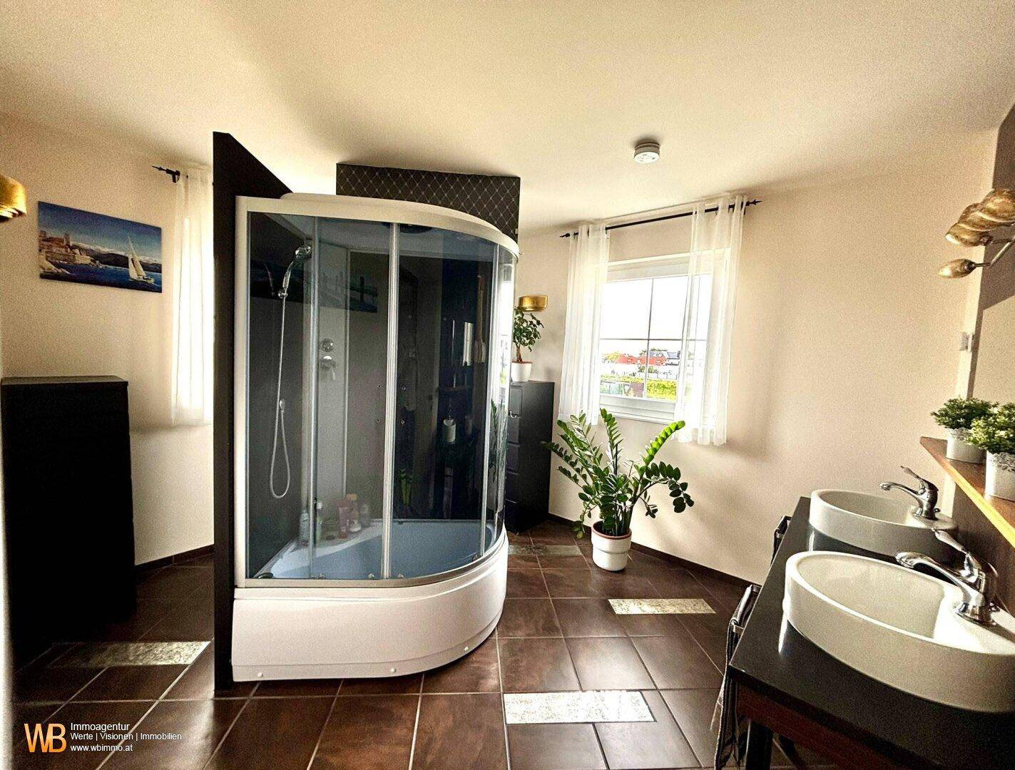 Geräumiges Badezimmer mit moderner Duschkabine, Doppelwaschbecken und einem großen Fenster.