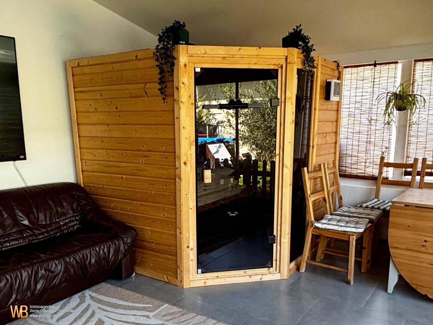 Nahaufnahme der Holzsauna im Wintergarten, umgeben von natürlichem Licht und Grün.