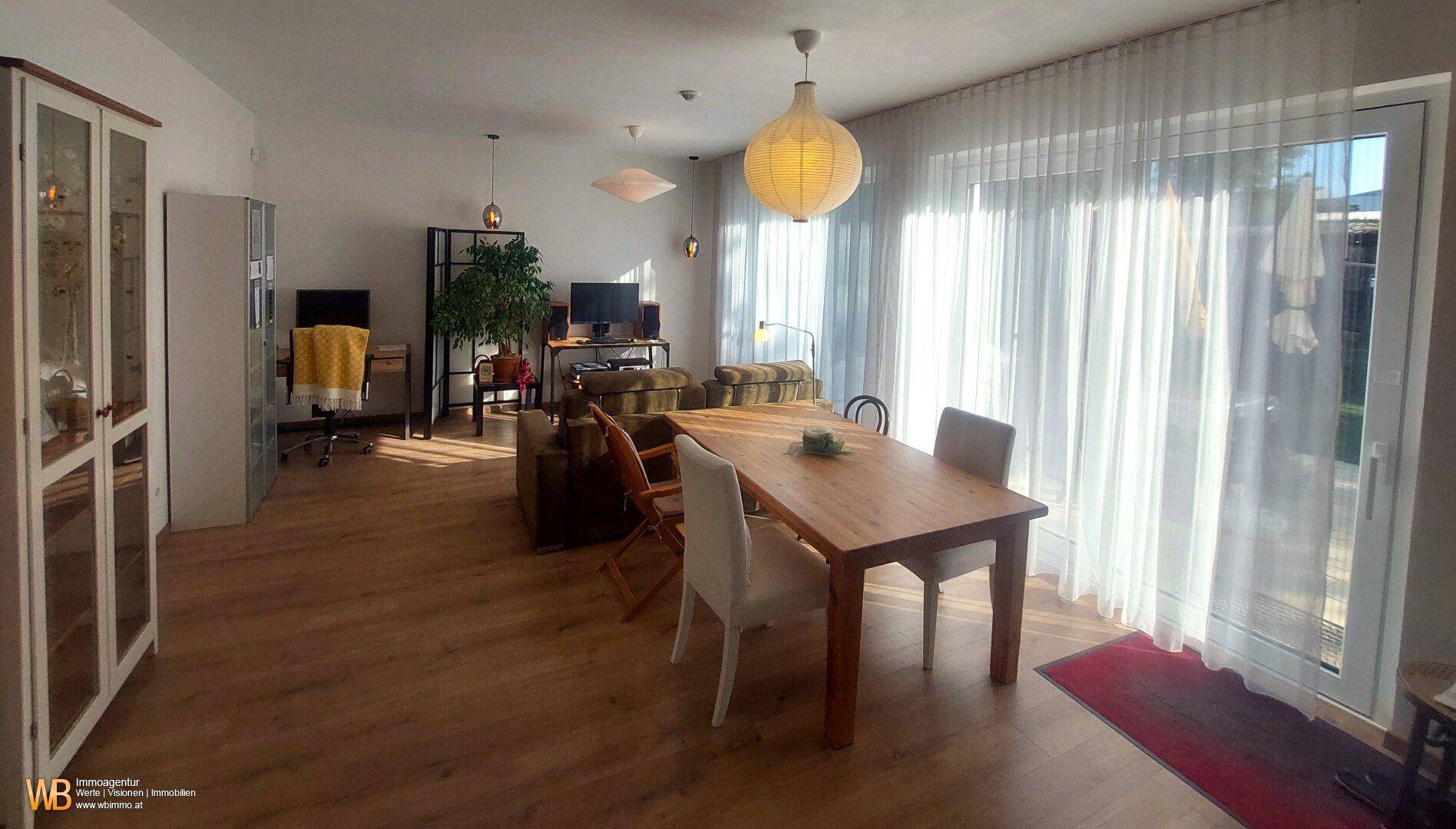 Geräumiger Wohn- und Essbereich mit viel Tageslicht, Holzboden und modernem Mobiliar.
