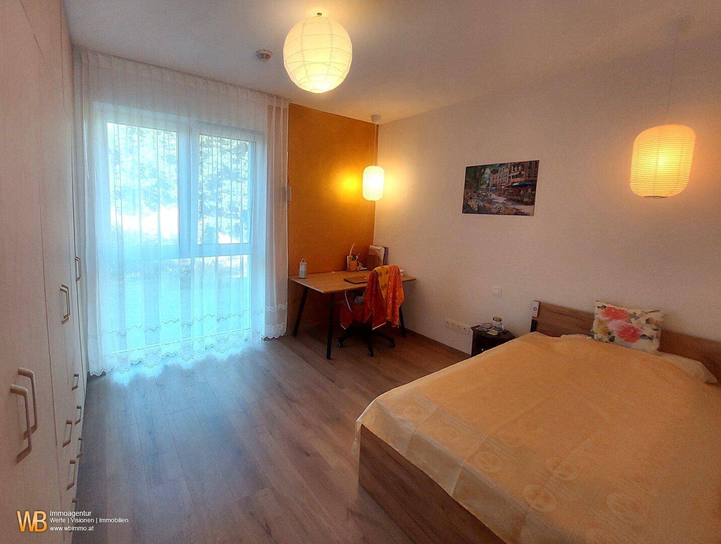 Helles Schlafzimmer mit Holzboden, großem Fenster, gelber Akzentwand und modernem Bett.