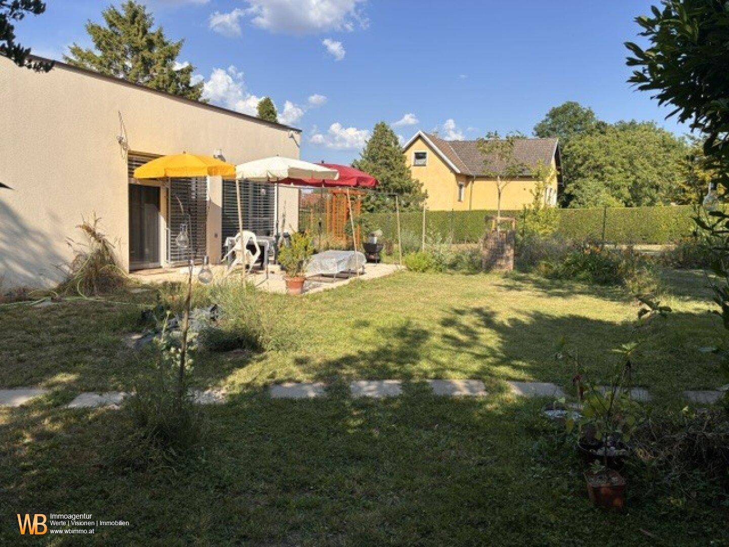 Weitläufiger Garten mit Rasenfläche, Terrasse und Blick auf die umliegende Natur.