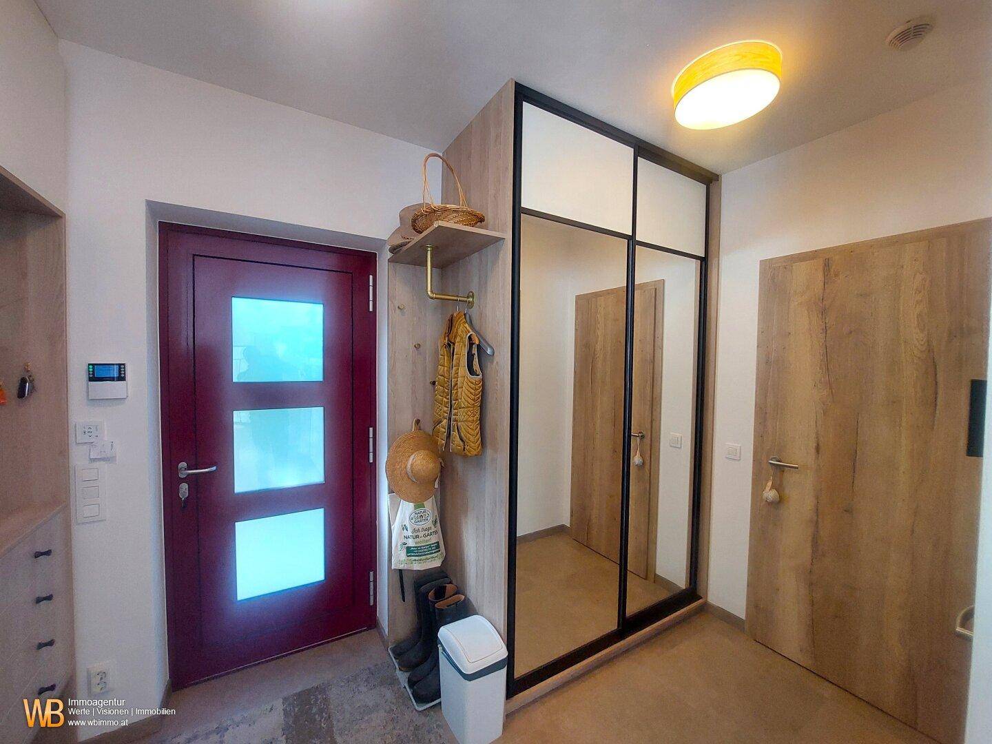 Eingangsbereich mit Spiegelschrank, Holztüren und praktischer Garderobe für den Alltag.
