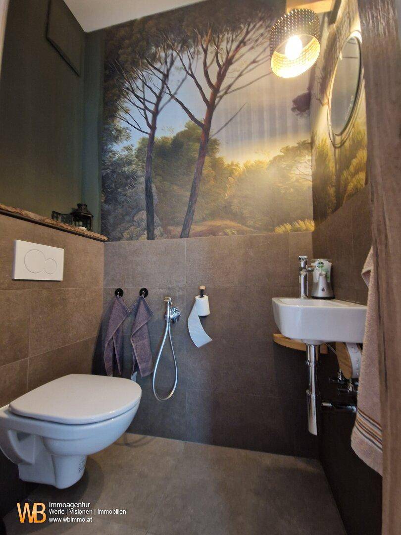 Gäste-WC mit dekorativer Wandtapete, Wand-WC und kleinem Waschbecken.