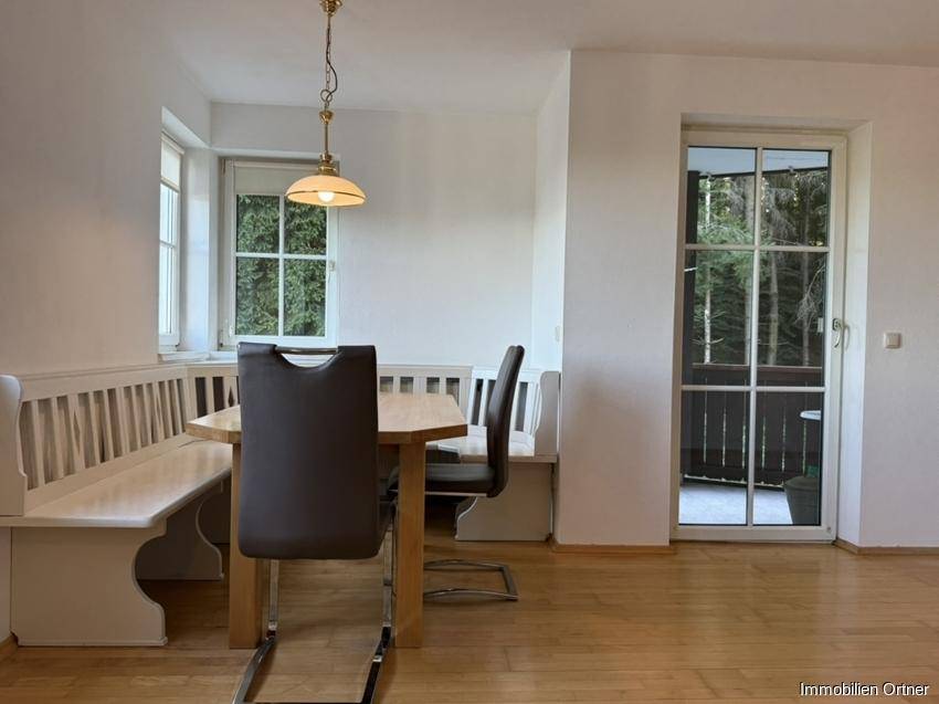 Gemütlicher Essbereich mit Holztisch, Eckbank und Zugang zu einem Balkon oder einer Terrasse.