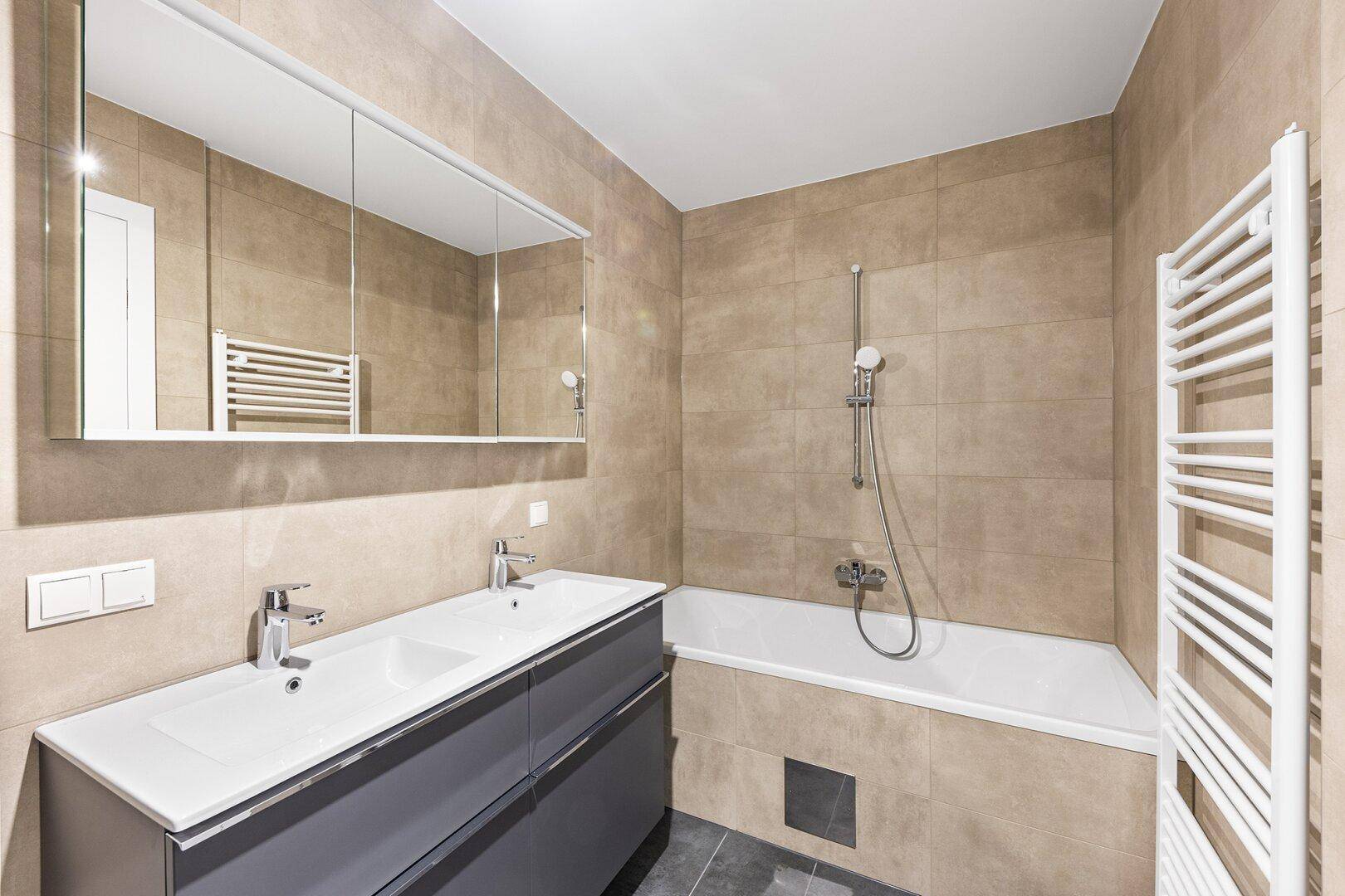 Modernes Badezimmer mit Badewanne, Doppelwaschbecken und beheiztem Handtuchhalter.