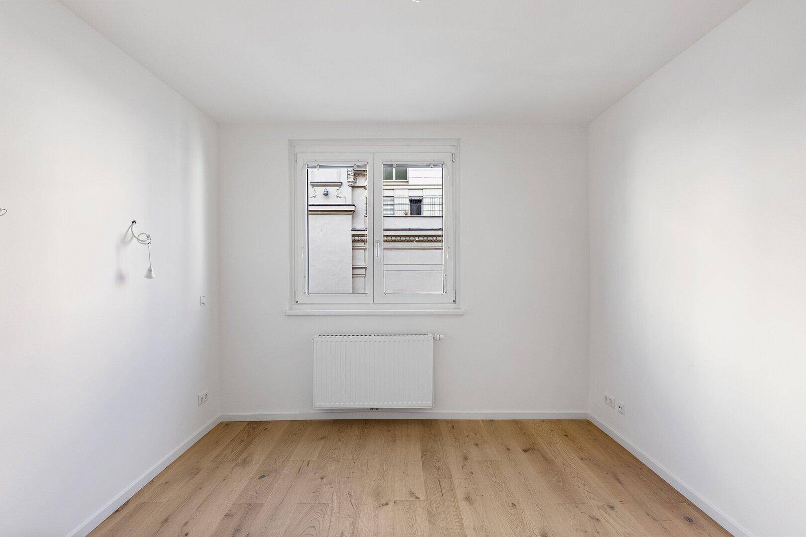 Geräumiges Schlafzimmer mit Holzboden und großem Fenster für viel Tageslicht.