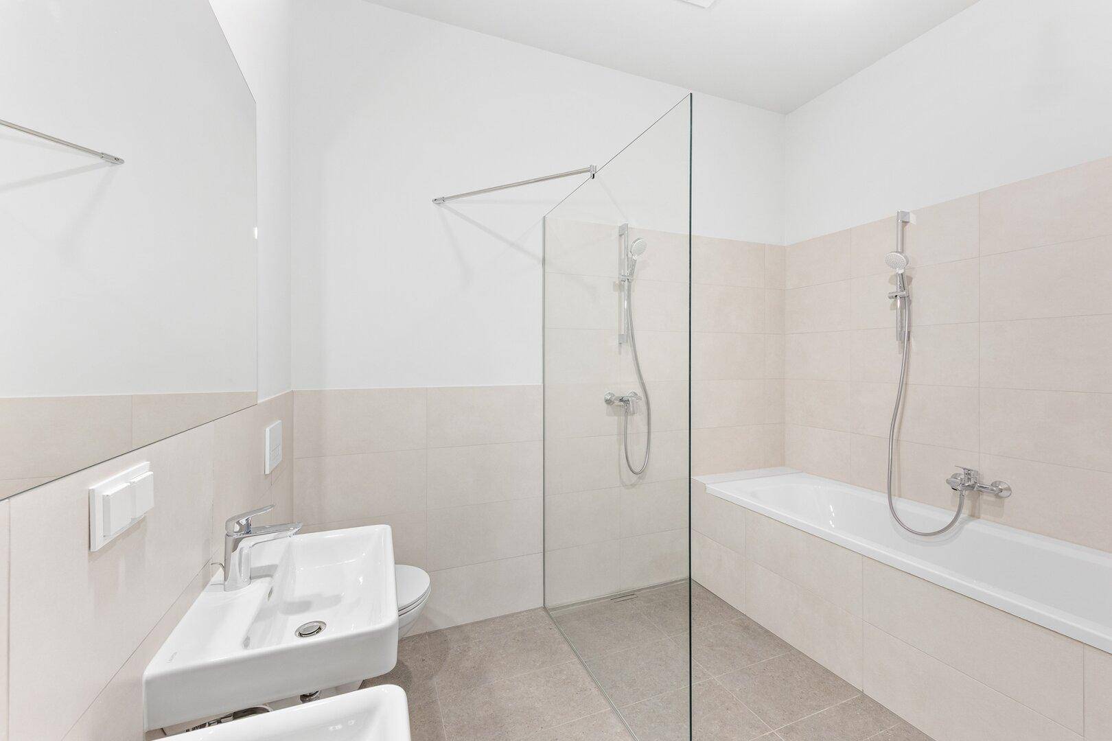 Modernes Badezimmer mit Badewanne, Dusche und hellen Fliesen.