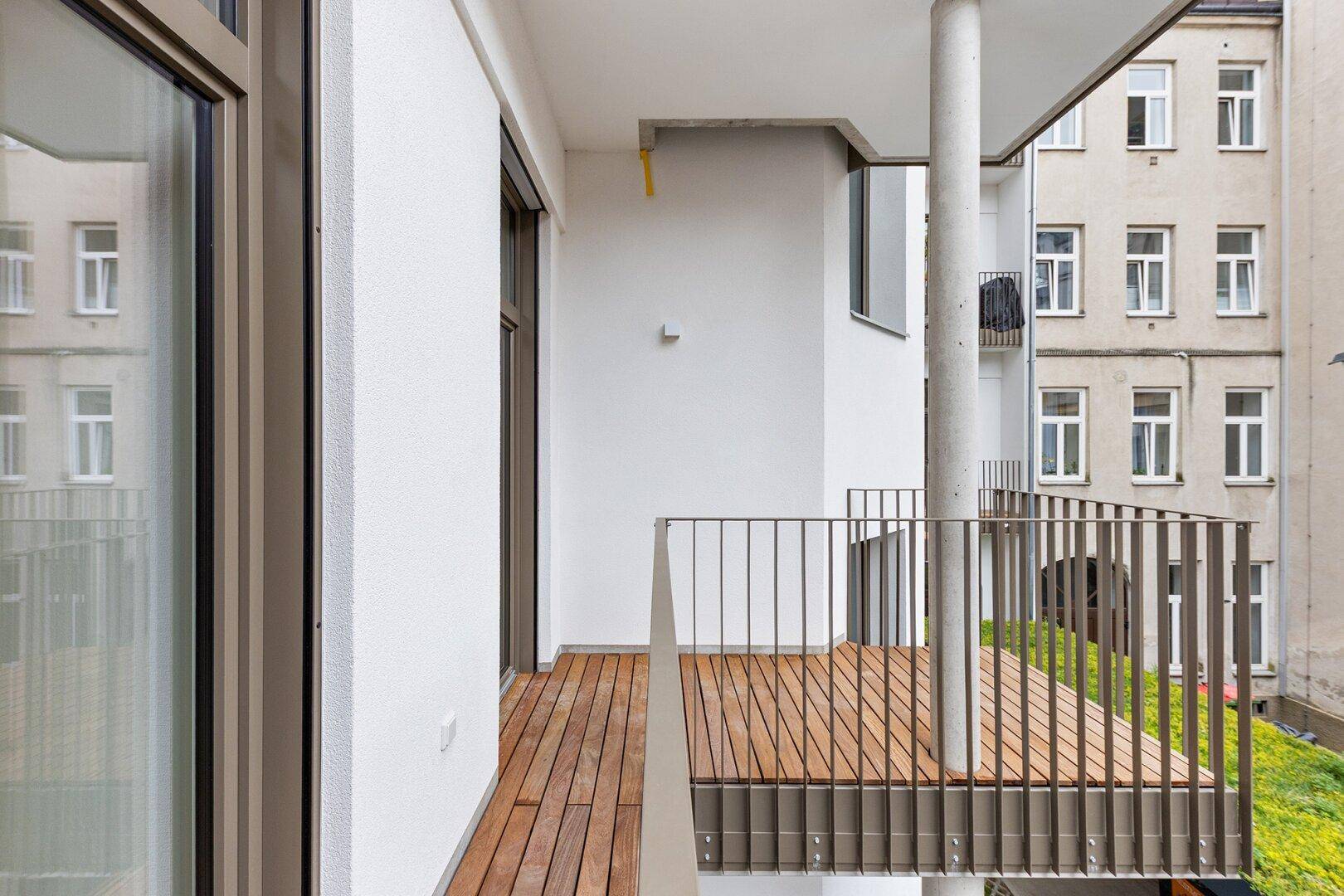 Moderner Balkon mit Holzbelag und Metallgeländer, ideal für entspannte Stunden im Freien.
