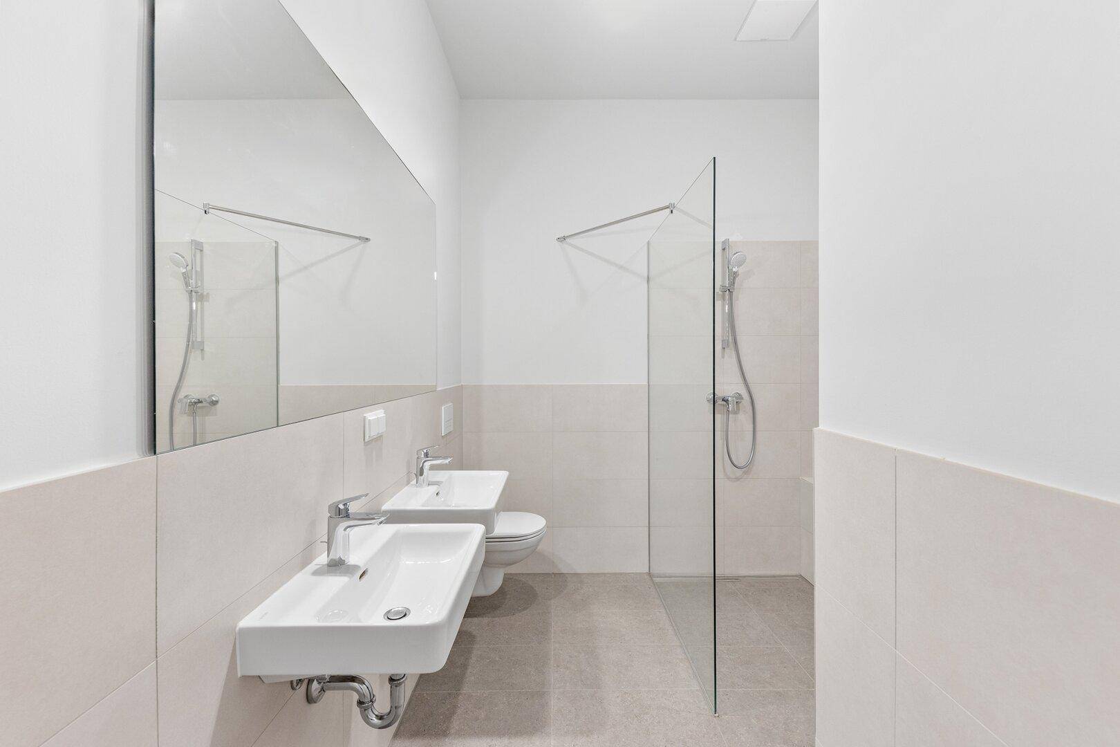 Zeitgemäßes Badezimmer mit zwei Waschbecken, Dusche und Badewanne in hellen Farbtönen.