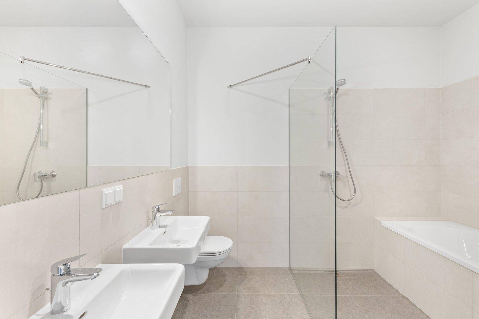 Modernes Badezimmer mit Doppelwaschbecken, Dusche, Badewanne und hellen Fliesen.