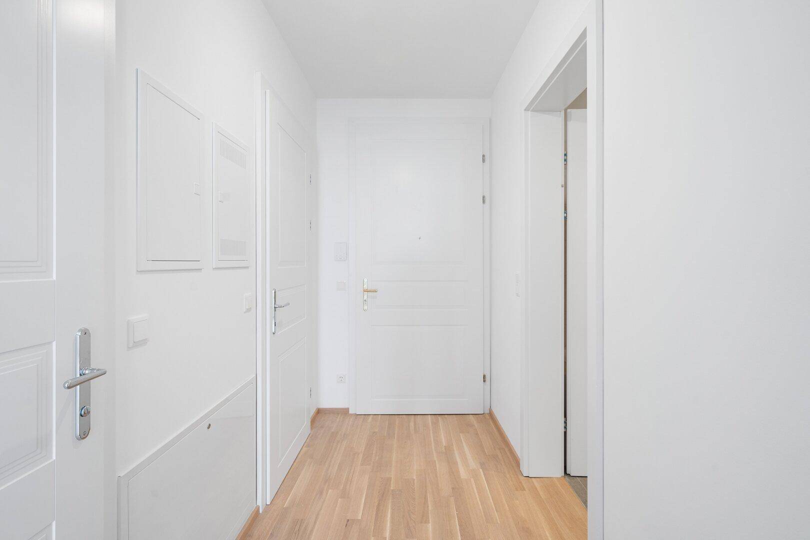 Moderner und heller Eingangsbereich mit hellem Holzfußboden und weißen Türen in einer Wohnung.