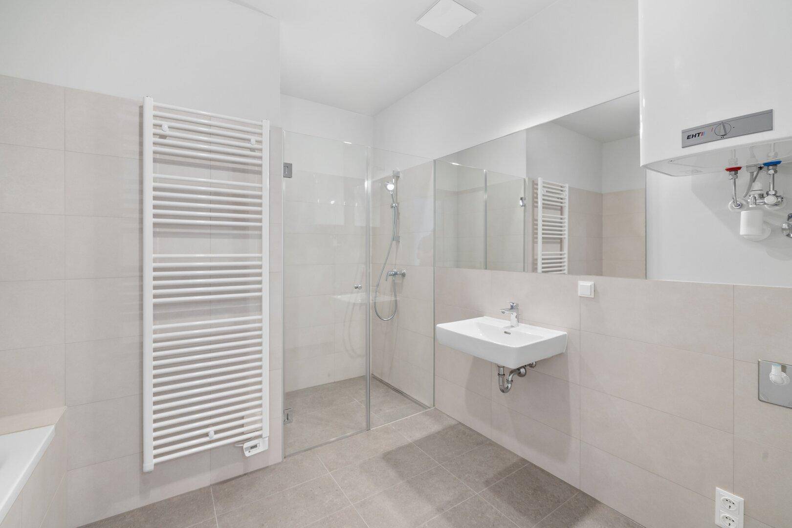 Modernes Badezimmer mit ebenerdiger Dusche, Einzelwaschbecken, großem Spiegel und Handtuchheizkörper.
