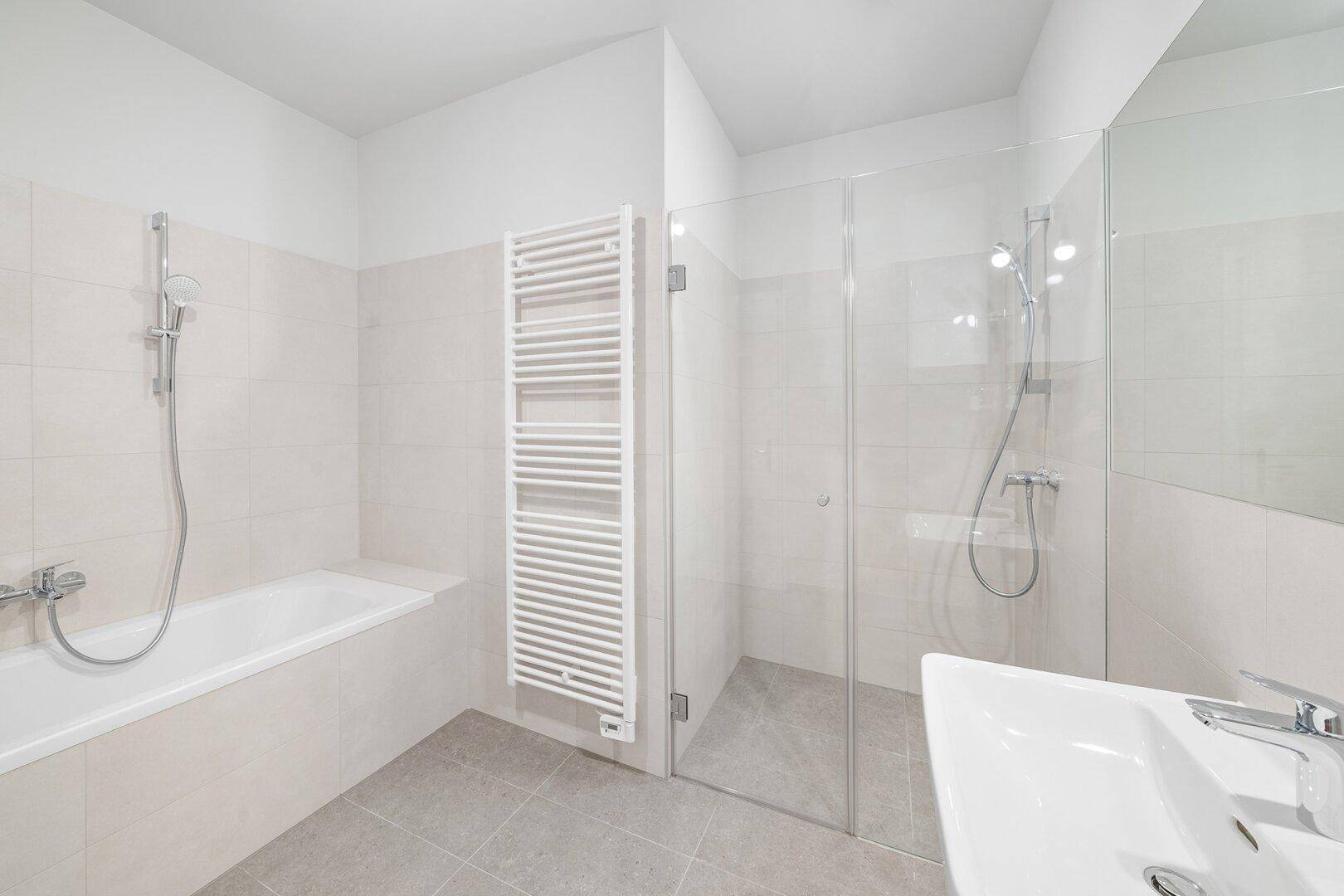 Helles Badezimmer mit Badewanne, ebenerdiger Dusche, Einzelwaschbecken und beheiztem Handtuchhalter.
