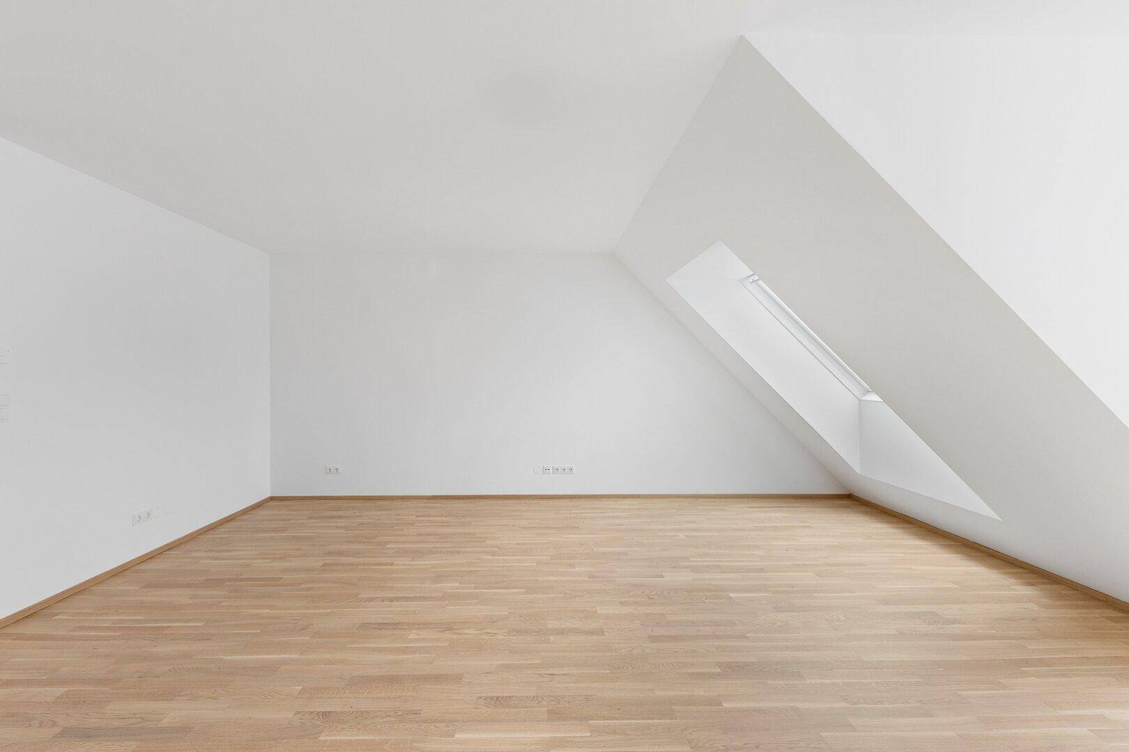 Heller Dachgeschossraum mit schrägen Wänden, Holzboden und viel Potenzial zur Gestaltung.