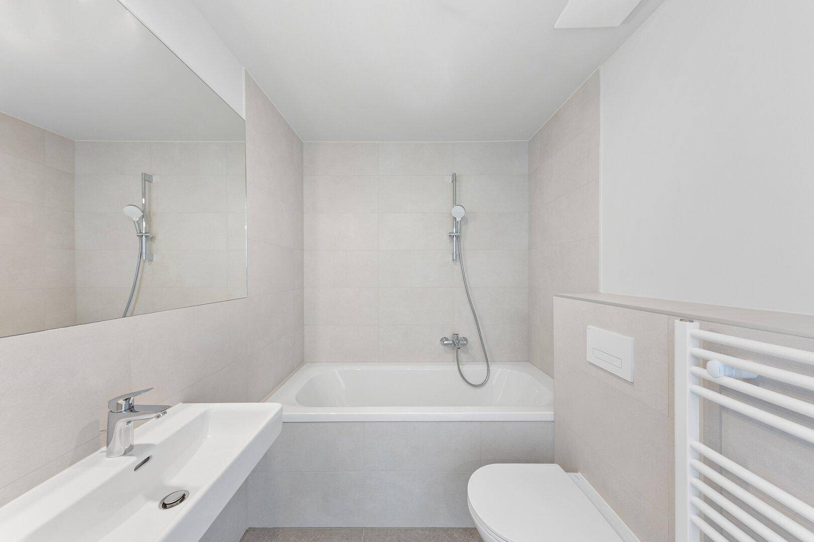 Modernes Badezimmer mit Badewanne, Wand-WC, Waschbecken und beheiztem Handtuchhalter.