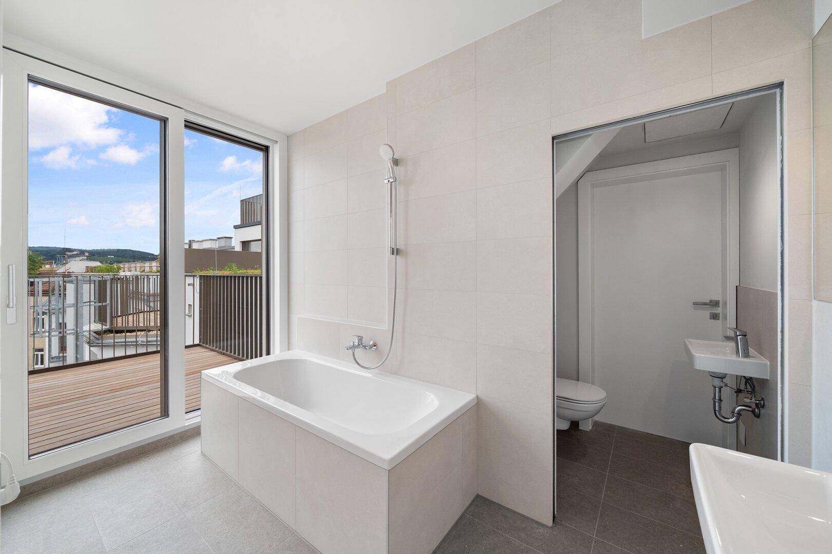 Modernes Badezimmer mit Badewanne, separatem WC und Zugang zu einer Dachterrasse.