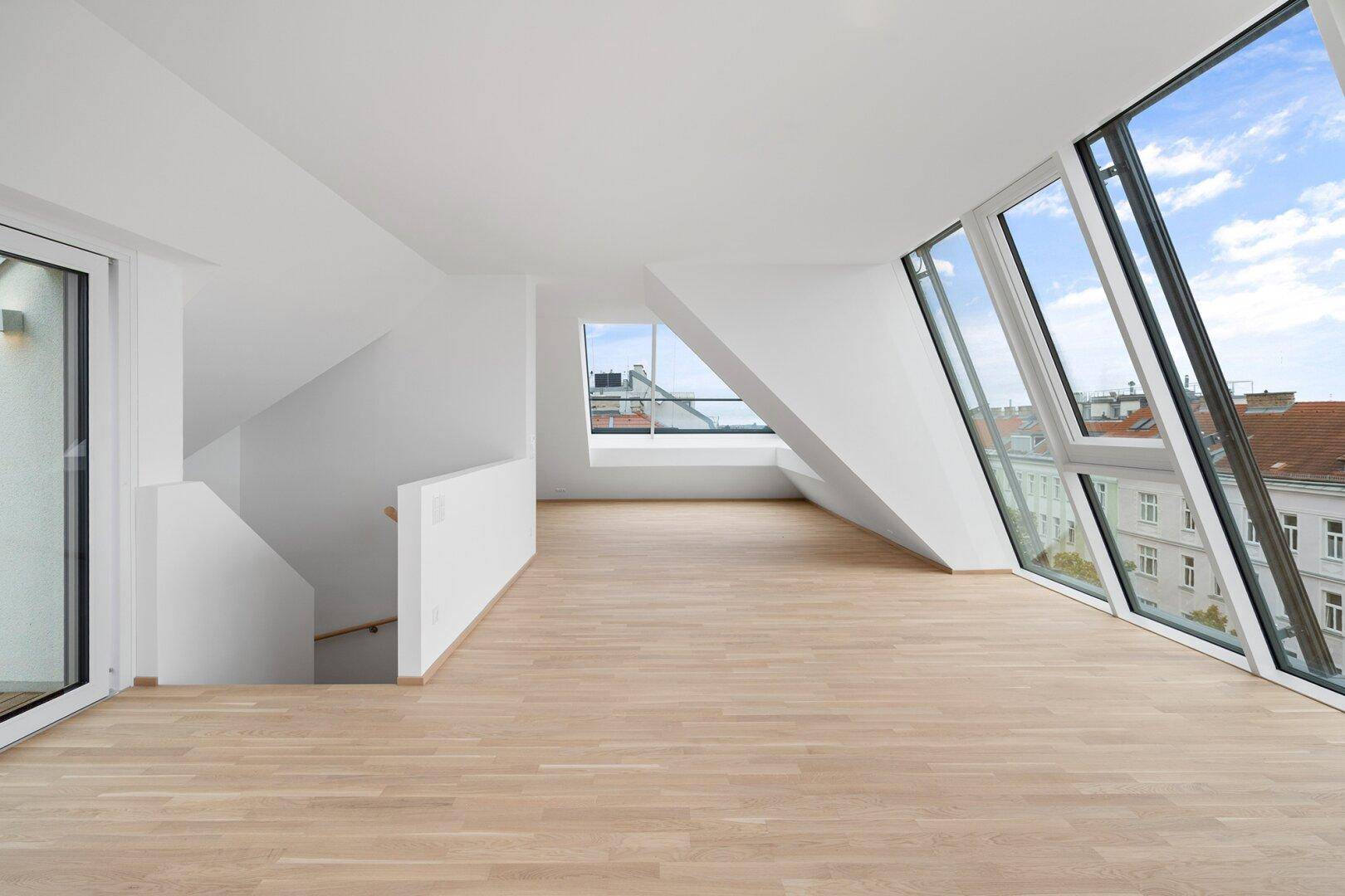 Heller Wohnbereich mit großen Fenstern, Stadtblick und Zugang zu einer Dachterrasse.