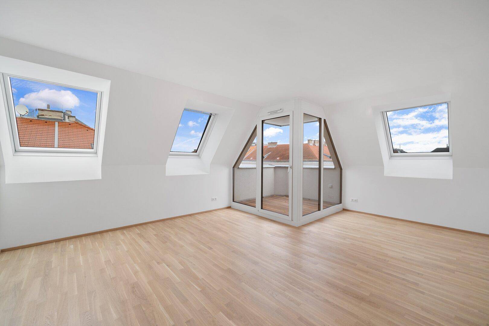 Geräumiges Dachzimmer mit Holzboden, Dachfenstern und integrierter Loggia mit Stadtblick.