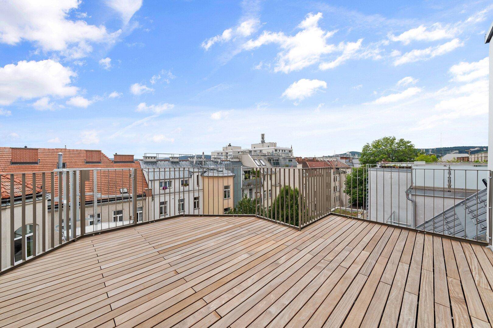 Große Dachterrasse mit Holzboden und weitem Panoramablick über die Stadtlandschaft.