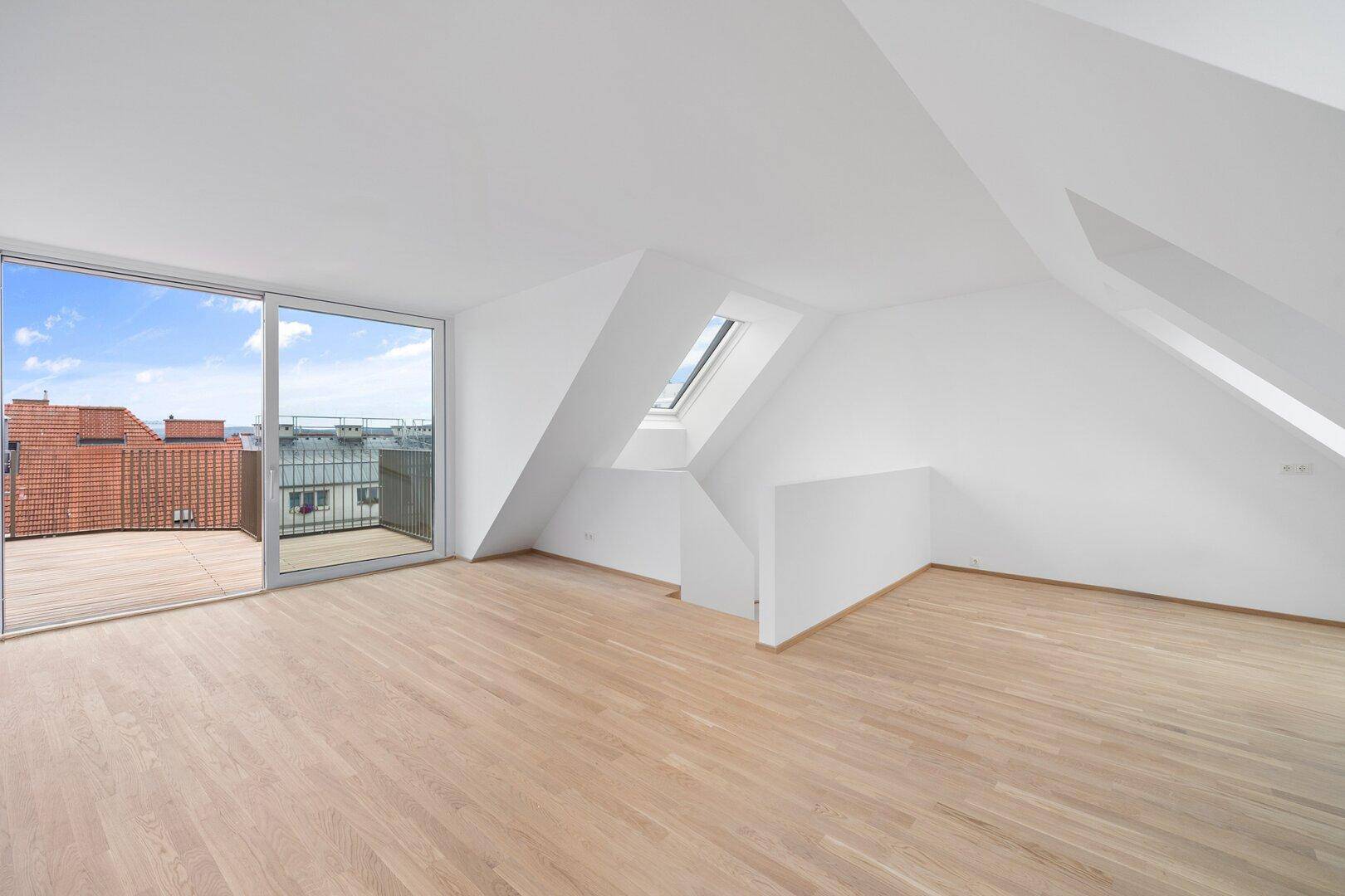 Geräumiges Dachgeschosszimmer mit Holzboden, Dachfenster und breitem Zugang zur Terrasse.