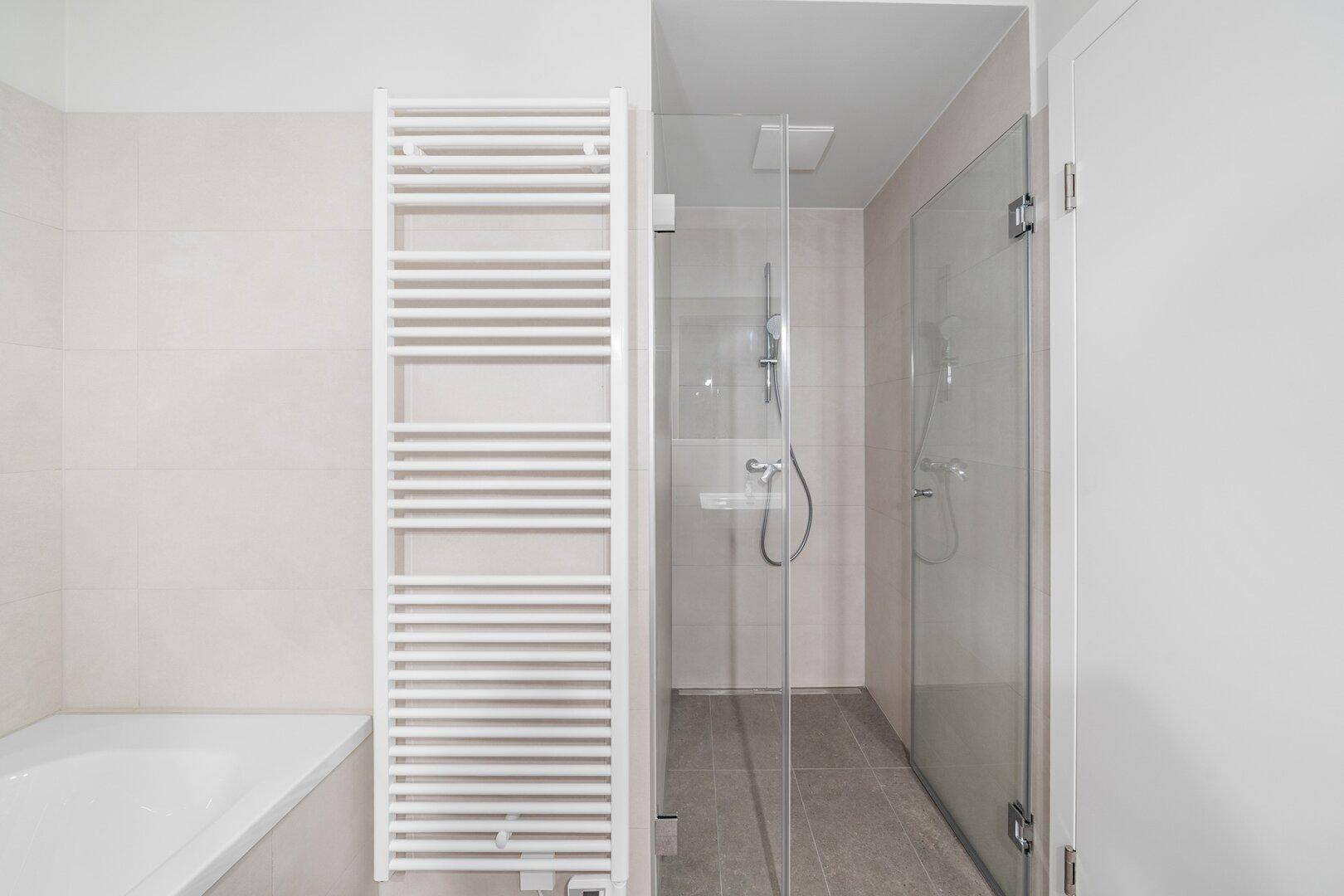 Modernes Badezimmer mit begehbarer Dusche, Badewanne und beheiztem Handtuchhalter.