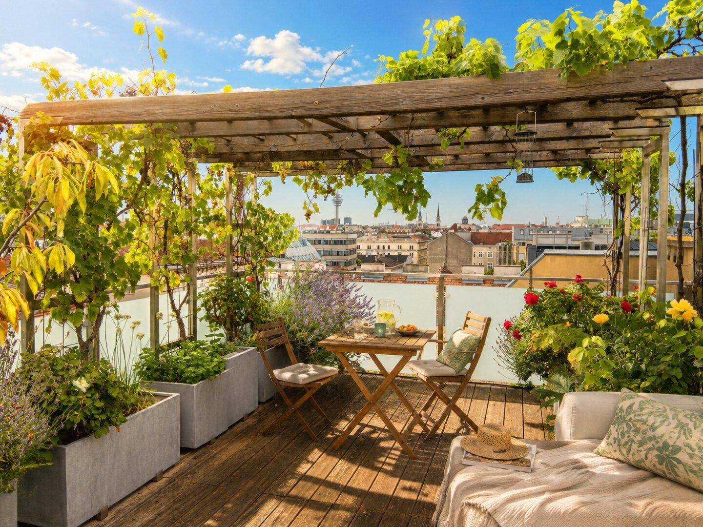Sonniger Dachgarten mit Pergola, gemütlichen Sitzgelegenheiten und weitem Blick über die Stadt.