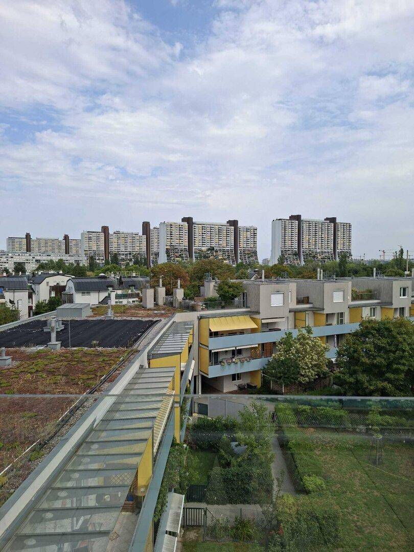 Panoramablick von oben auf eine Wohnsiedlung mit modernen Gebäuden und einer gläsernen Überführung.