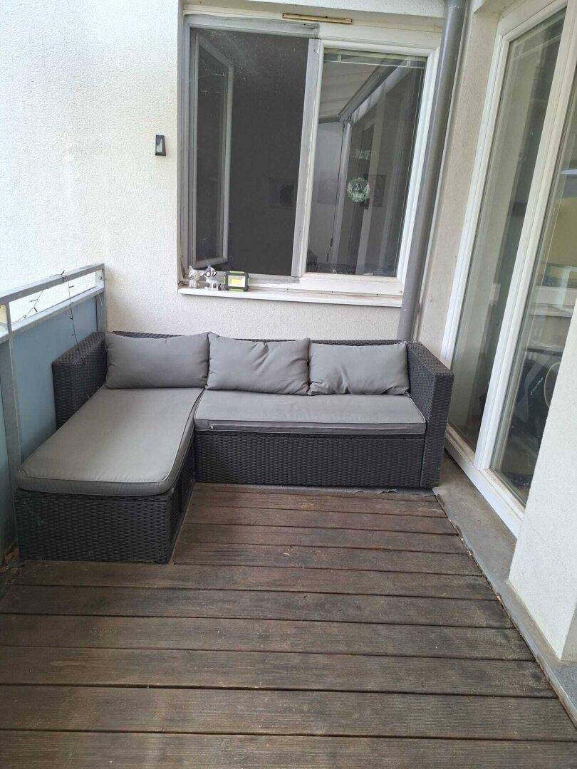 Gemütlicher Balkon mit Holzboden und bequemen Outdoor-Sitzmöbeln für entspannte Stunden.