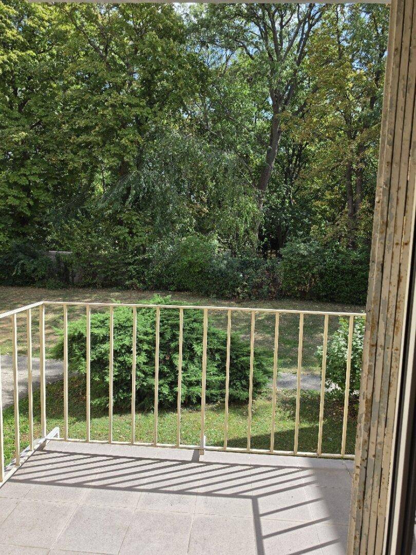 Nahaufnahme des Balkons mit Gittergeländer und weitem Blick in die grüne Umgebung.