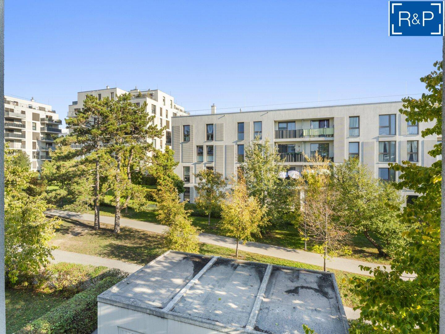Panoramablick auf eine moderne Wohnanlage mit Grünflächen und mehreren Gebäuden.