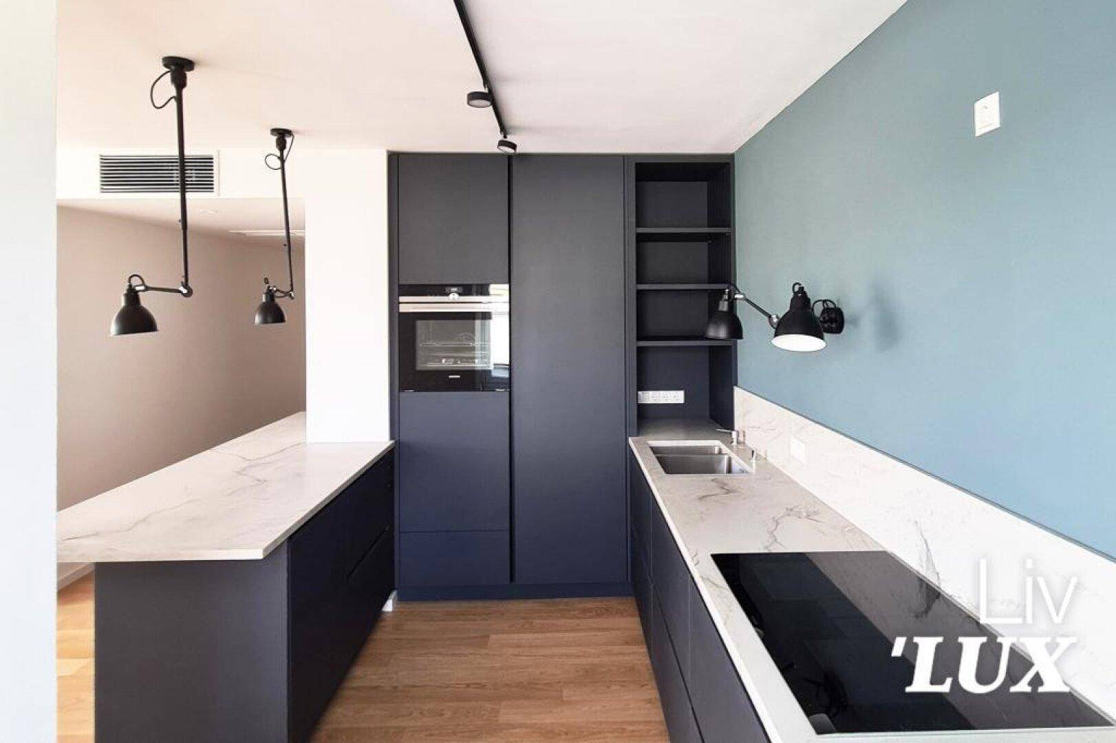 Moderne Küche mit dunkelblauen Schränken, Marmorarbeitsplatten und Holzboden.