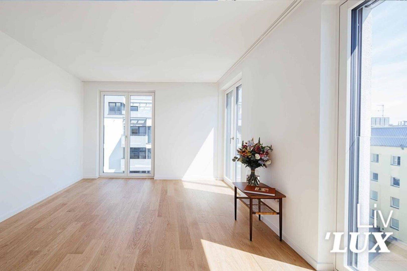 Geräumiges, helles Wohnzimmer mit Holzboden und Zugang zu einem Balkon.