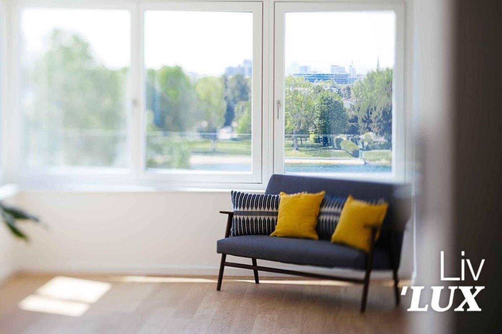 Helles Wohnzimmer mit Holzboden, großem Fenster und Blick ins Grüne.