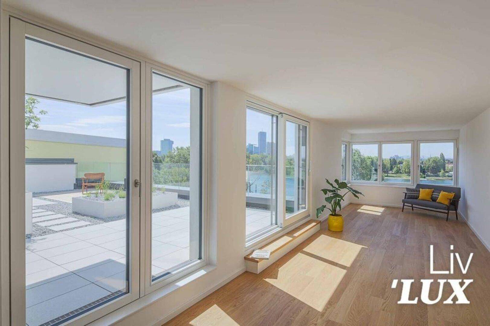 Lichtdurchflutetes Wohnzimmer mit Holzboden, großen Fenstern und Seeblick.