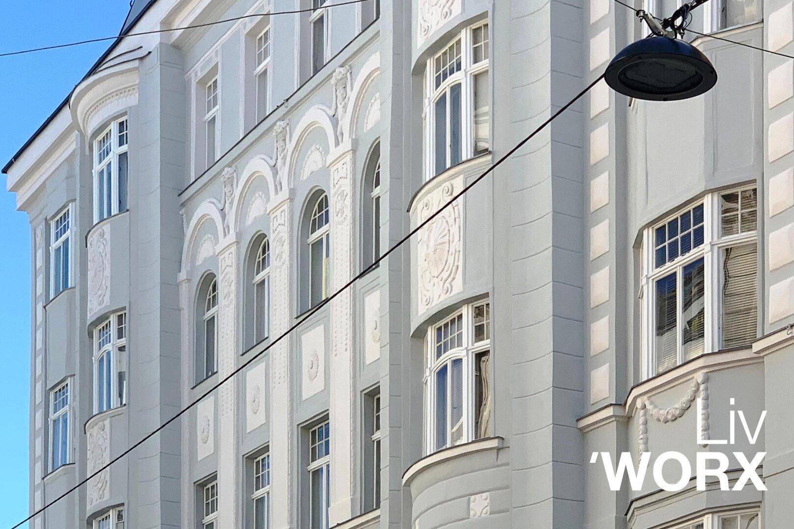 Prächtige Fassade eines Altbaus mit vielen Fenstern und reichen architektonischen Verzierungen.
