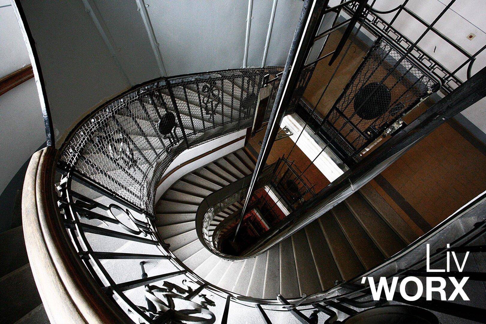 Elegante Wendeltreppe mit kunstvollem Metallgeländer in einem historischen Gebäude.