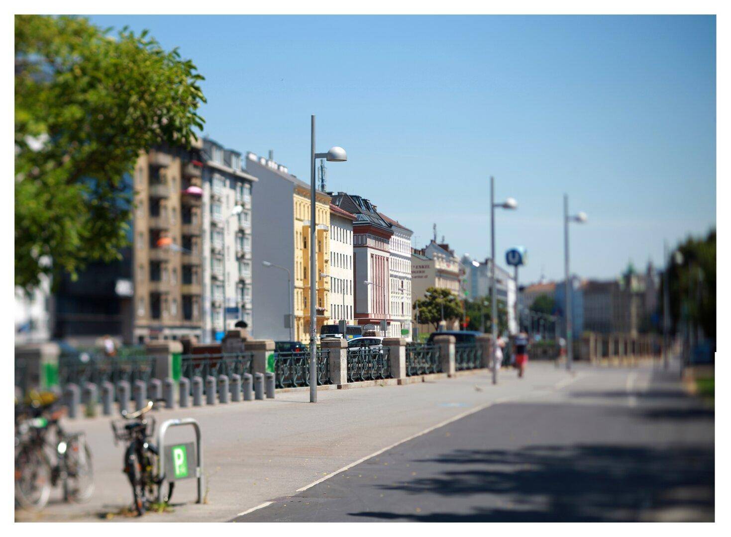 Eine belebte Straße mit historischen Gebäuden, Fahrrädern und einem Gehweg unter blauem Himmel.