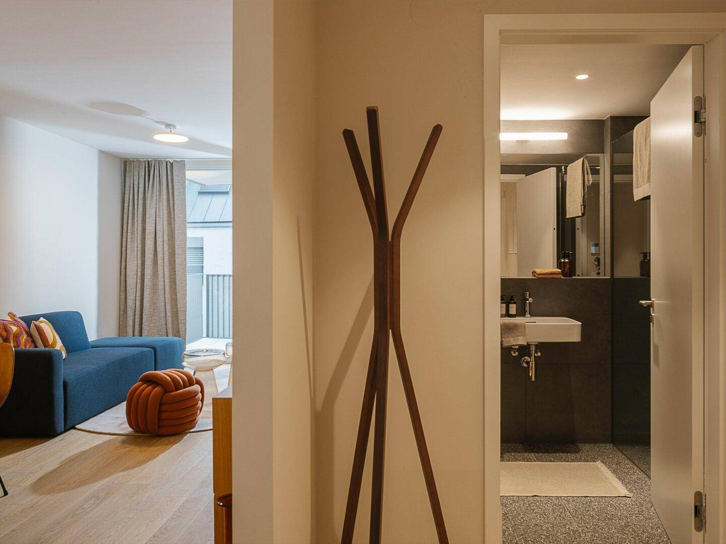 Eingangsbereich mit Garderobe, der in ein helles Wohnzimmer und ein modernes Badezimmer führt.