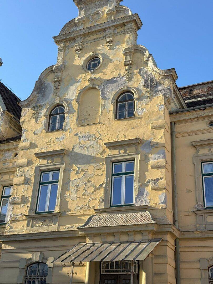 Nahaufnahme der historischen Fassade mit dekorativen Giebeln und deutlichen Abnutzungserscheinungen.