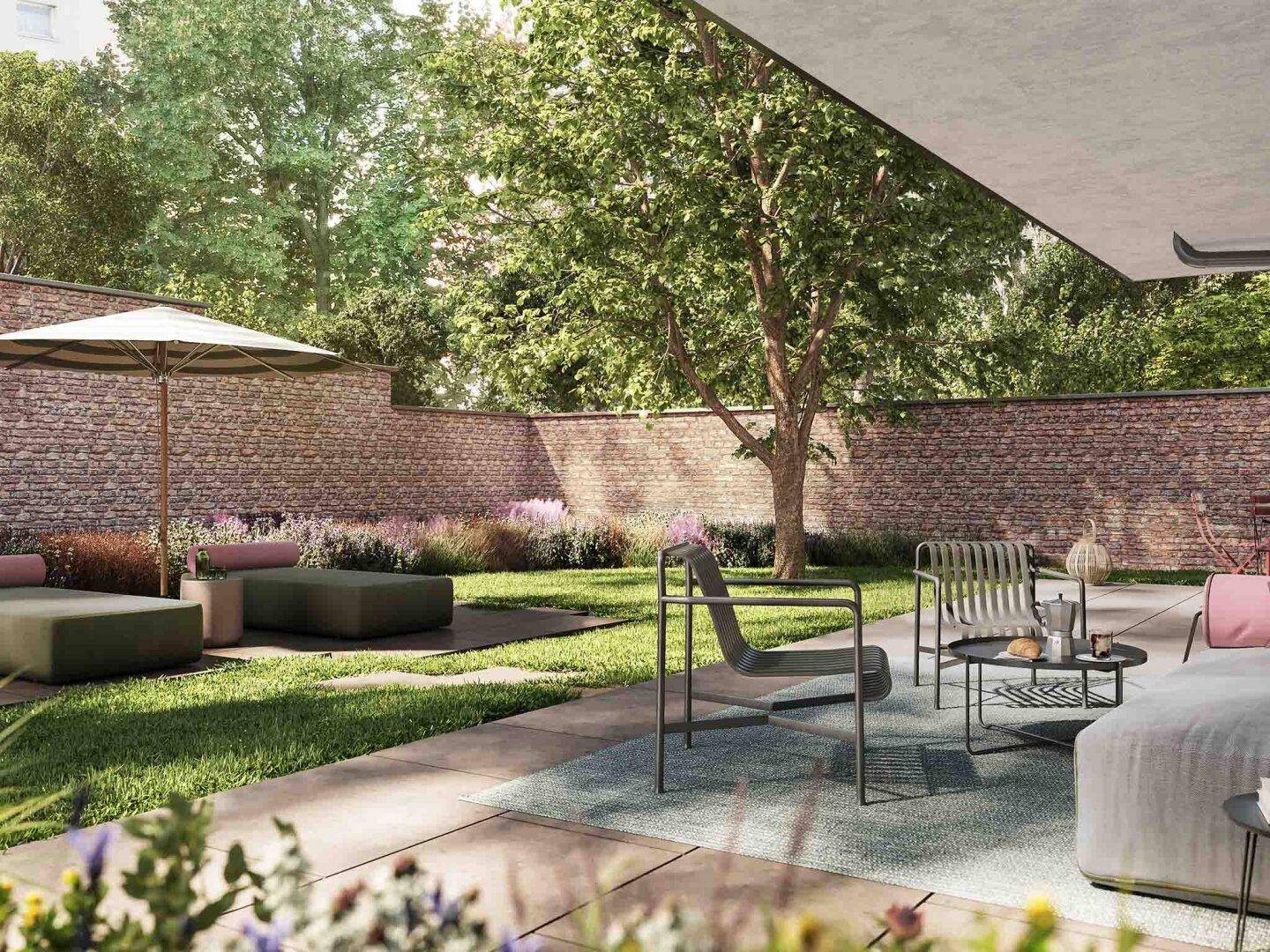 Großer Garten mit gepflasterter Terrasse, modernen Lounge-Möbeln und altem Baumbestand, umgeben von einer Steinmauer.