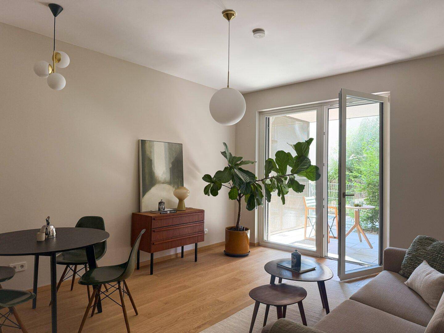 Heller Wohn-Essbereich mit Holzboden, modernen Leuchten und direktem Zugang zur Terrasse.