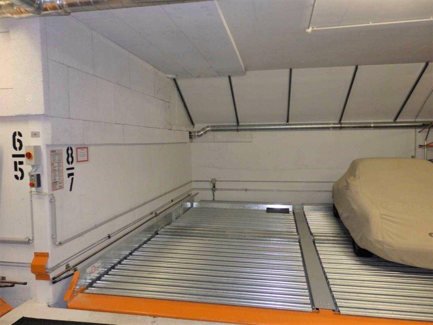 Detailansicht eines Doppelparkers in der Tiefgarage mit einem abgedeckten Fahrzeug.