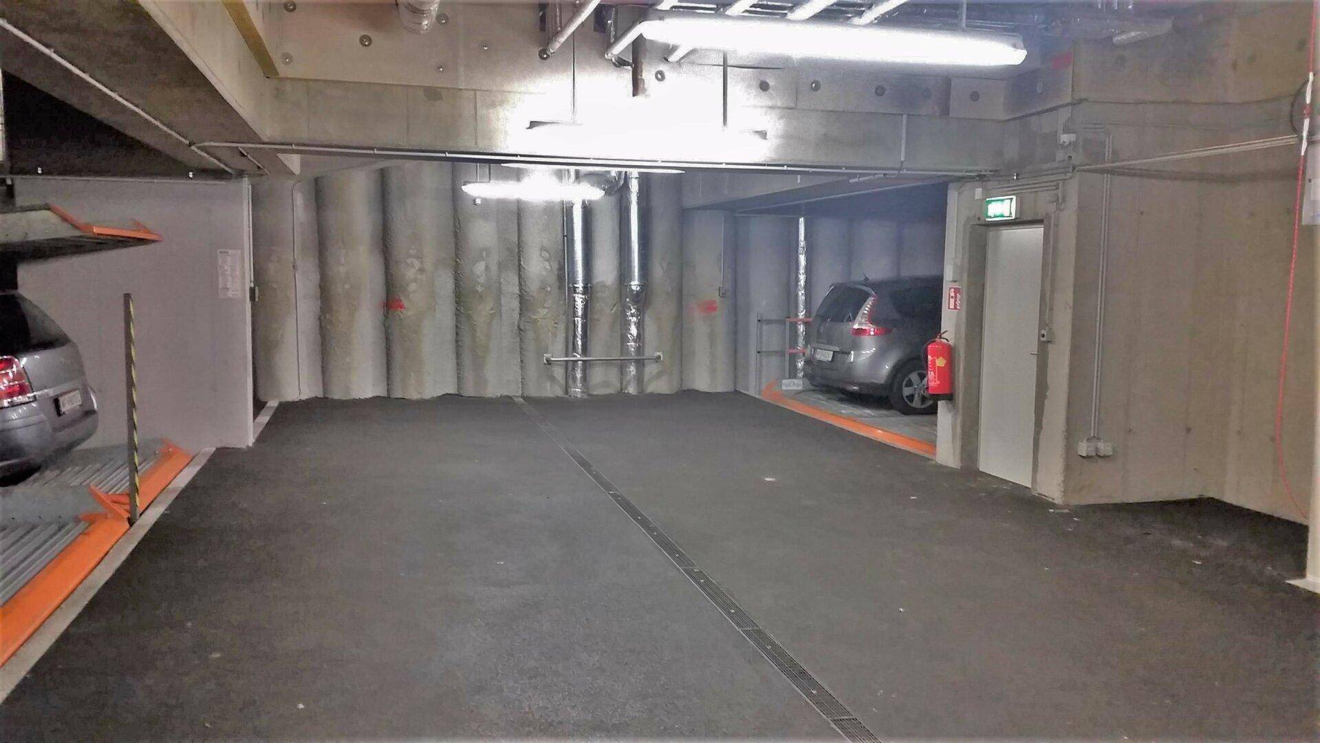 Geräumige Tiefgarage mit mehreren Stellplätzen, Betonwänden und einem geparkten Fahrzeug.