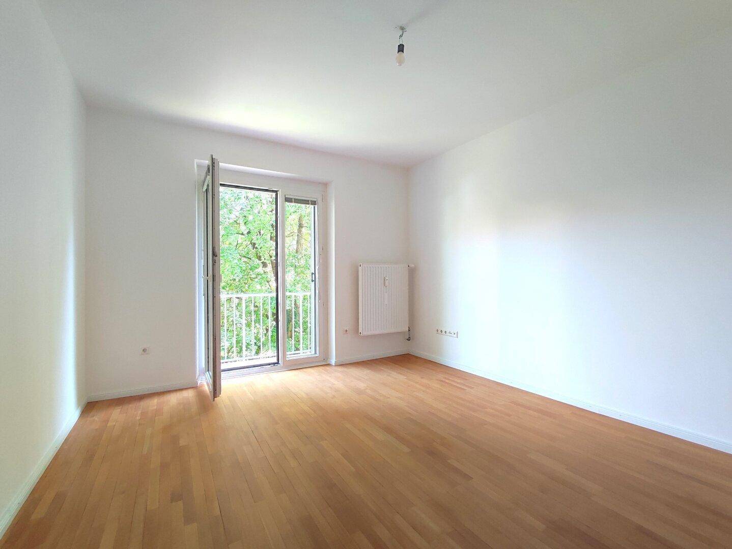 Geräumiger, heller Raum mit Holzboden und direktem Zugang zum Außenbereich.