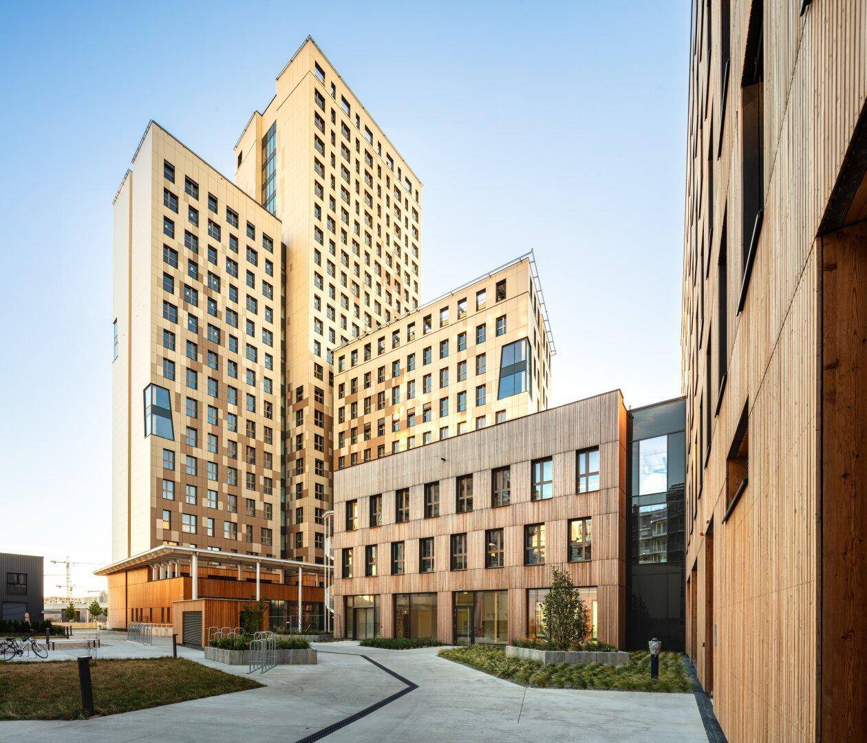 Zeitgenössische Gebäude mit Holzverkleidung und großen Fenstern in einer urbanen Umgebung.