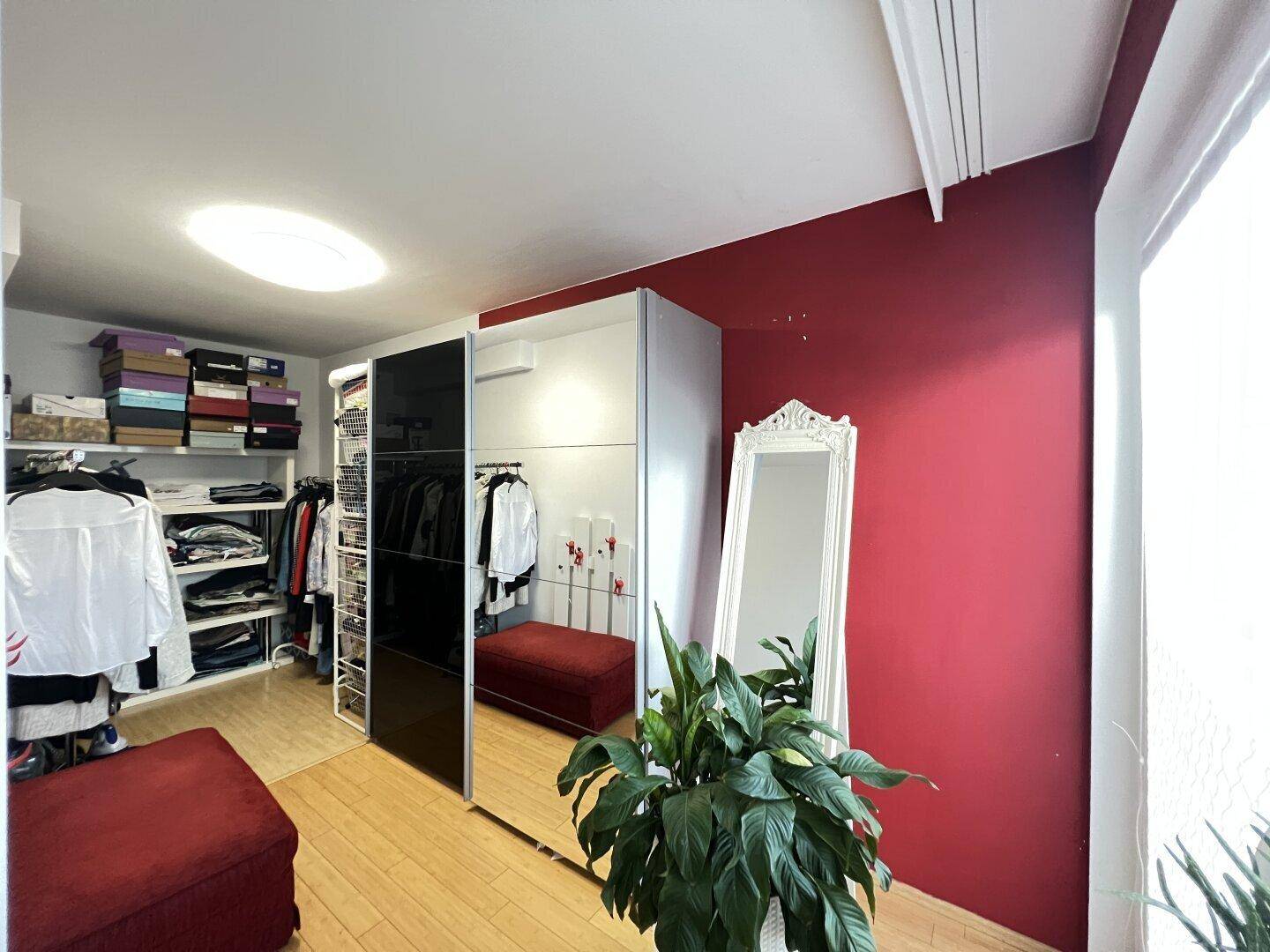 Geräumiger begehbarer Kleiderschrank mit Regalen, Kleiderstangen und Spiegel.