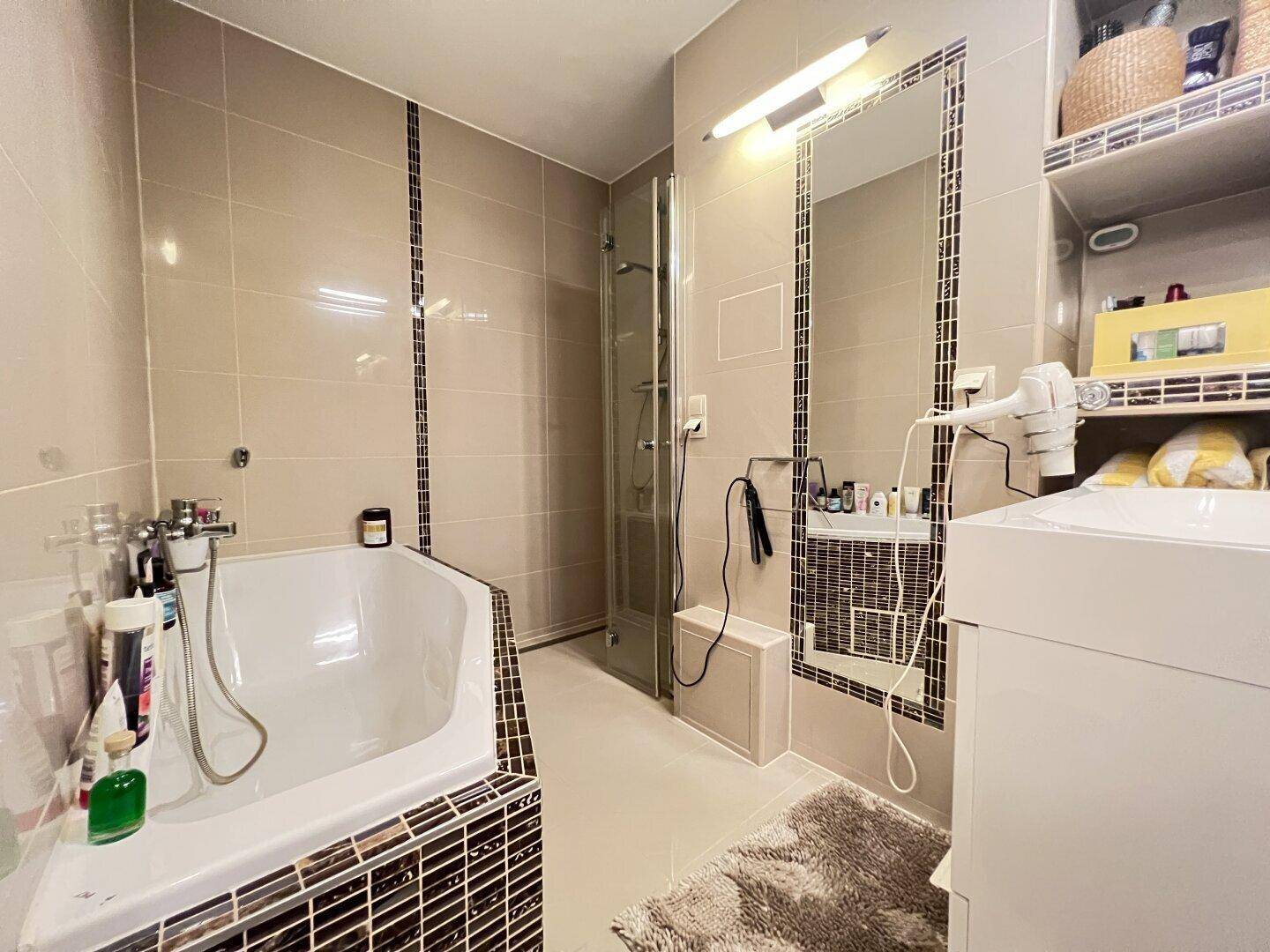 Modernes Badezimmer mit Eckbadewanne, Dusche und beigefarbenen Fliesen.