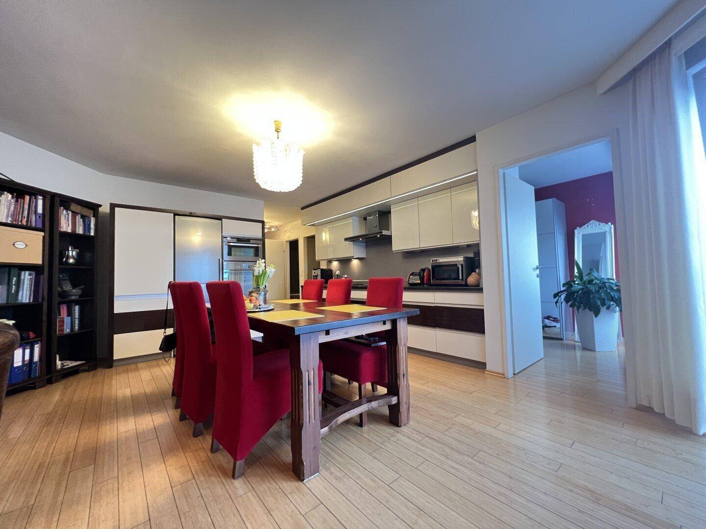 Offener Essbereich mit Zugang zum Balkon und Blick auf die moderne Küche.