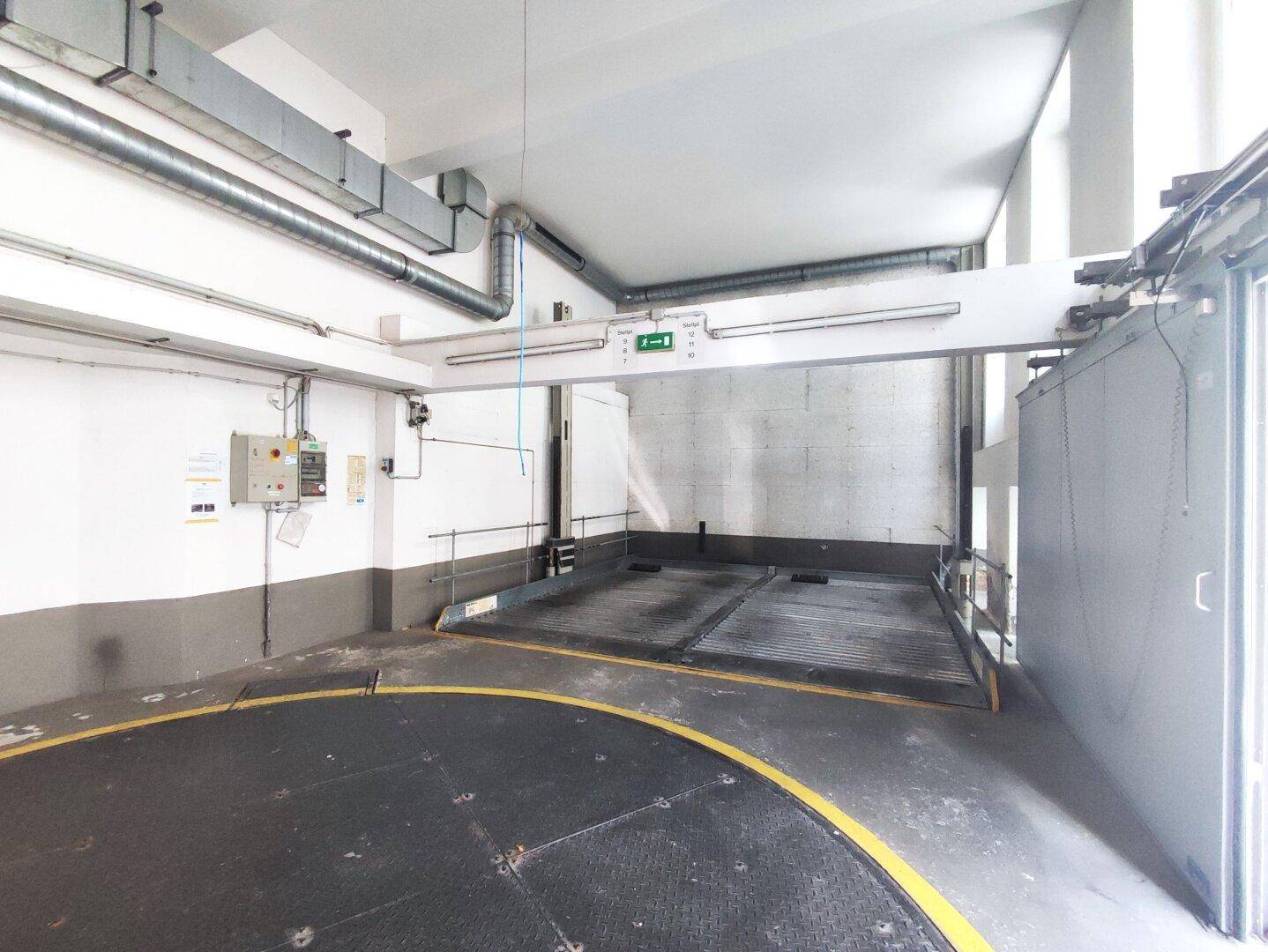 Leere Tiefgarage mit Autodrehbühne und mechanischem Parksystem, bereit für Fahrzeuge.