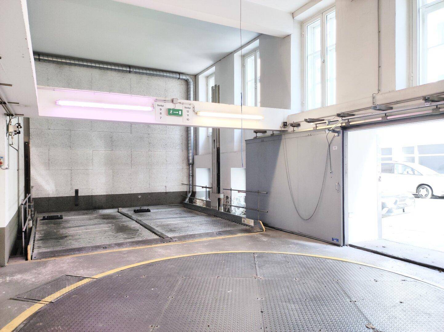 Leere Tiefgarage mit Autodrehbühne und mechanischem Parksystem, bereit für Fahrzeuge.